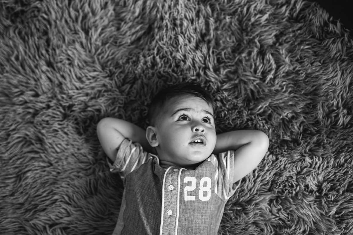 chilled hands behind head black and white family snuggle on the bed lifestyle photography yasmin anne