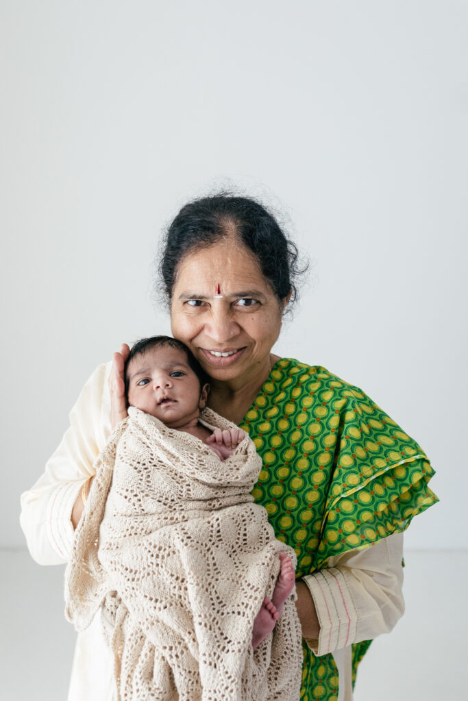 Indian grandmother, dressed in a traditional sari poses with her newborn grandson 