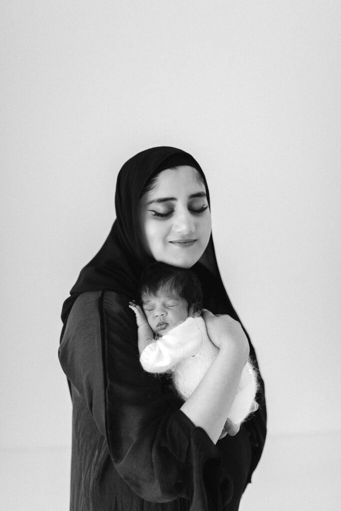 muslim woman wearing a Hijabposes with her newborn baby 