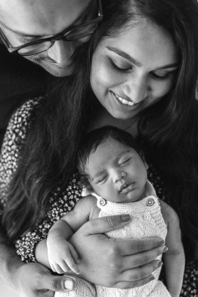 Mum and dad hold newborn baby boy and smile