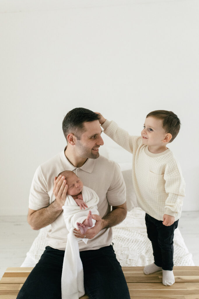 Father, son and newborn baby pose together