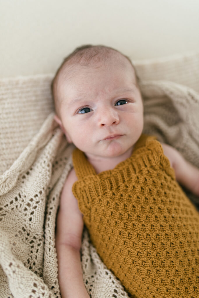 Newborn baby looks at the camera with eyes wide open 