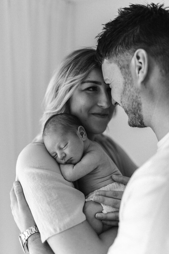 Mother smiles as she holds her newborn baby in her arms 