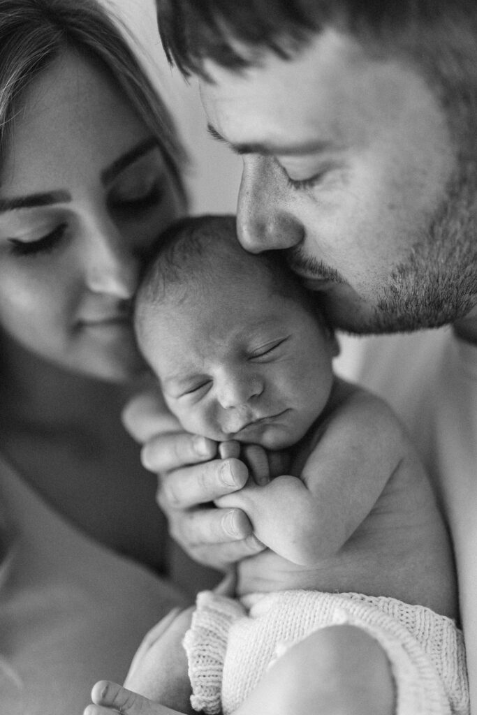 Parents kiss newborn on head 