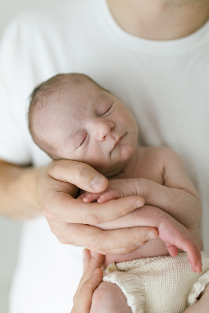 Newborn baby asleep in dads arms