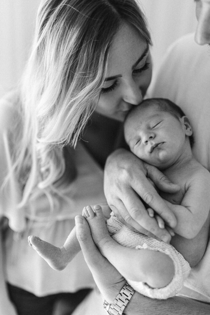 Close up photograph of mother kissing baby on the head 