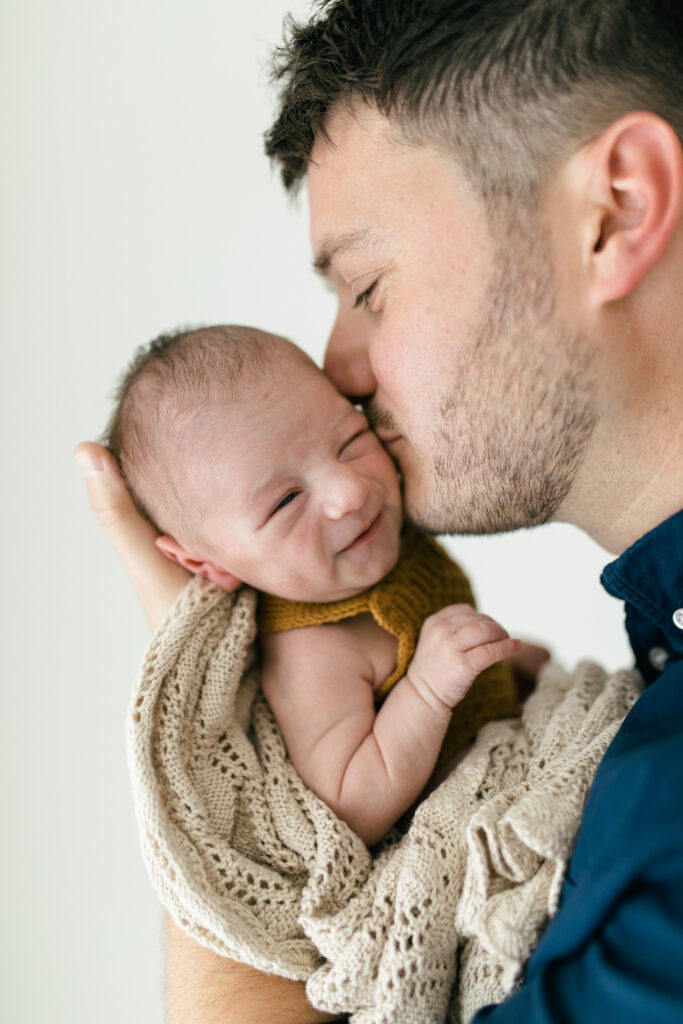 Dad kisses newborn baby on the head 