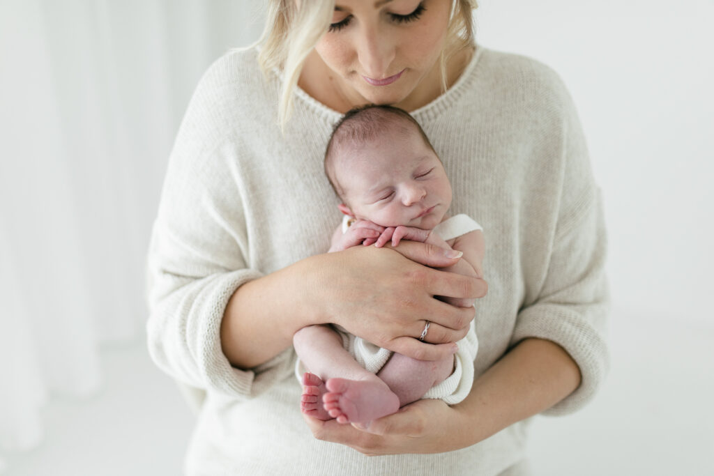 Mum and newborn baby cuddle during photoshoot for baby's first year 