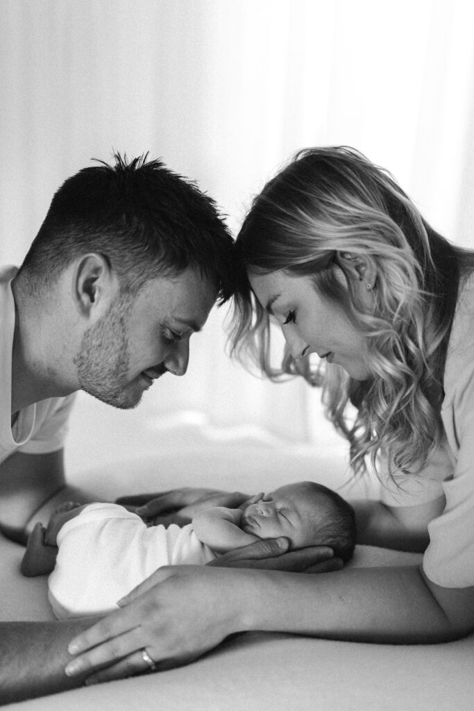 mum and dad smiling at newborn baby