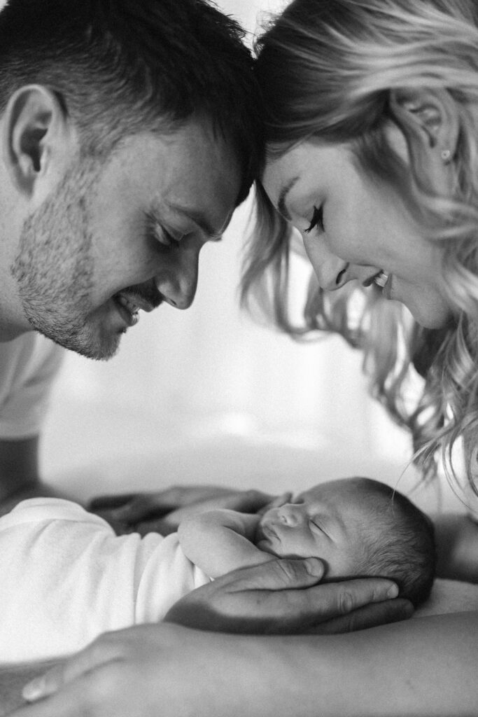 Mum and dad hold baby ans smile at baby 