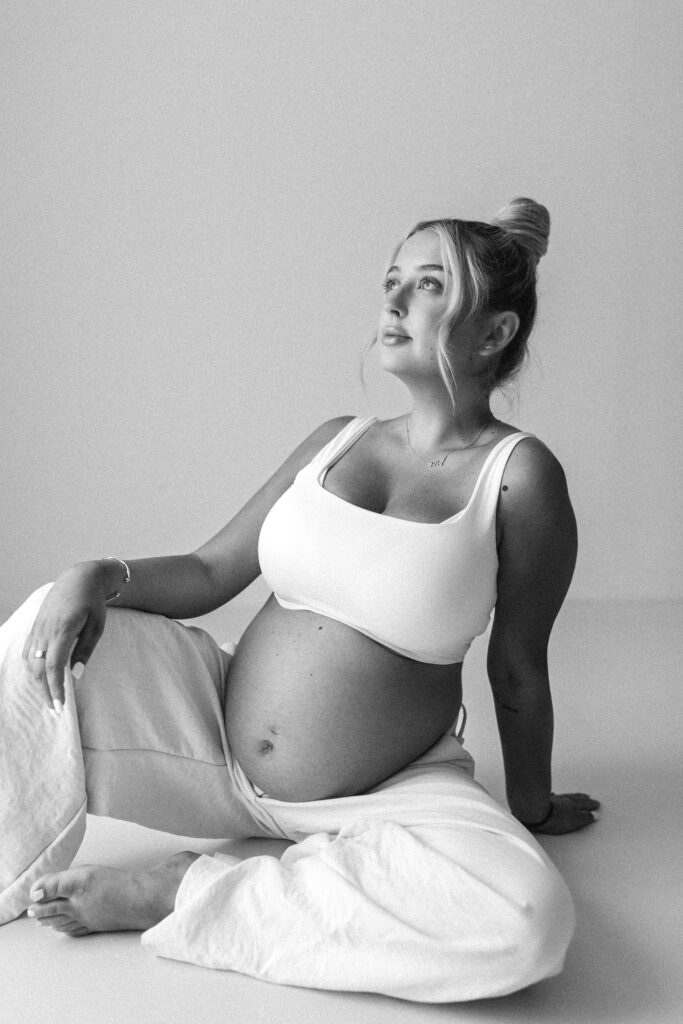 Pregnant mother sits on the floor and looks up to the sky, black and white image 