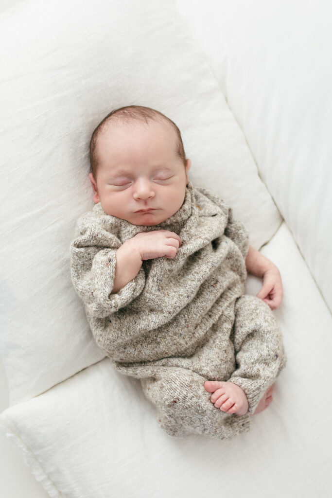 2 week old newborn boy lies on pillows asleep 