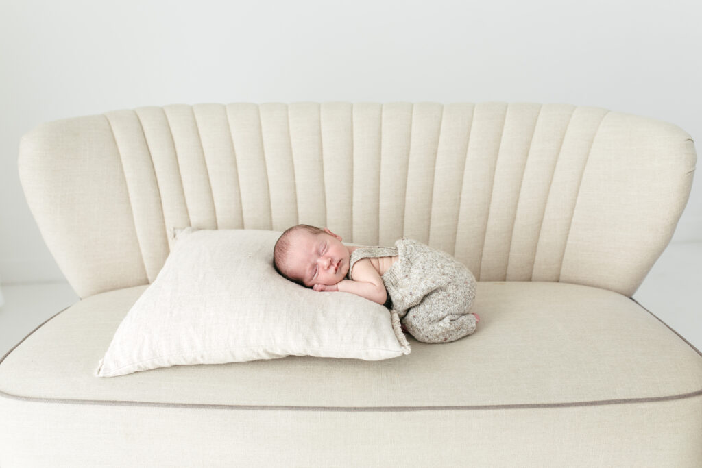 Newborn baby boy lies on his tummy on a sofa 